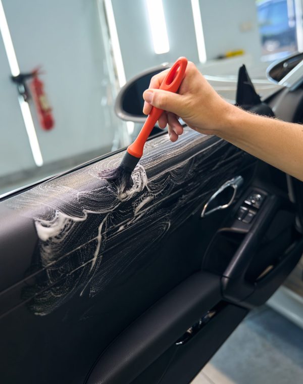 Auto repair shop employee uses a brush to treat the interior of a car, he uses a special product