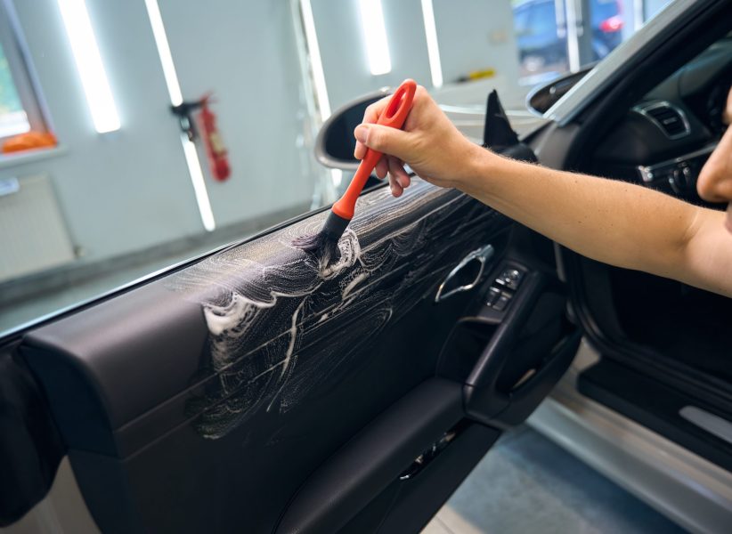 Auto repair shop employee uses a brush to treat the interior of a car, he uses a special product